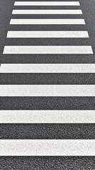 Fototapeta premium The aerial perspective showcases a vacant pedestrian crossing at an intersection in a city, highlighting the stark white stripes against the asphalt and surrounding greenery