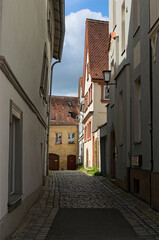 Typical narrow pedestrian medieval cobblestone street along ancient buildings in historical part of Bamberg, Upper Franconia district in Bavaria, Germany. Travel and tourism concept