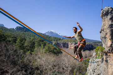 A tightrope walker walks along a cable stretched over a canyon.
