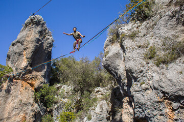 A tightrope walker walks along a cable stretched over a canyon.