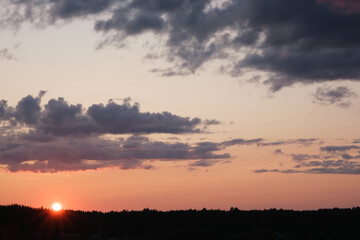 Sunset sky with dark clouds over the forest on the horizon