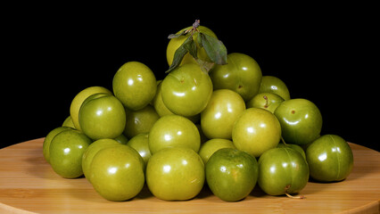 Close-up footage of green plum fruit on black background.