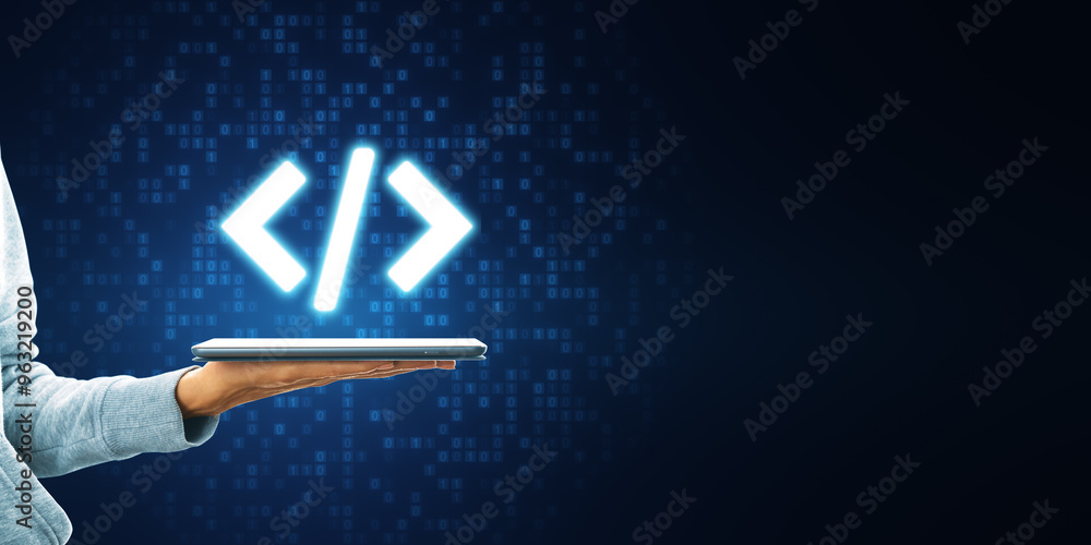 Poster bright coding symbol on a tablet screen held by a person in a dark background.