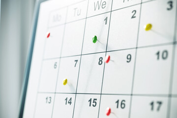 Closeup of a calendar with colorful pins marking important dates. 3D Rendering