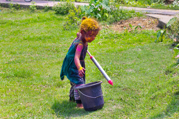 Little girl holding pichkari with water color during holi