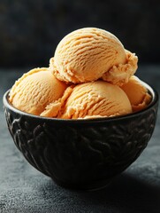 Close-Up of Delicious Scoops of Orange Ice Cream in a Black Bowl on a Dark Background