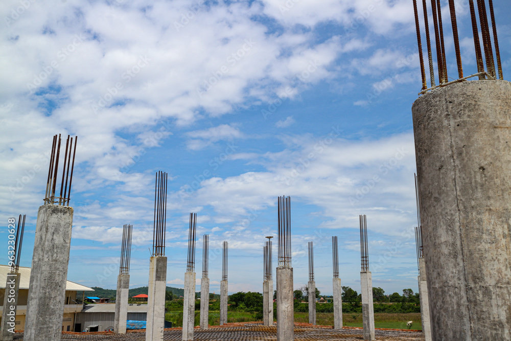 Poster a view of a construction site with multiple concrete pillars supporting the framework of a building 