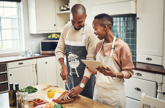 Kitchen, cooking and couple with tablet, online and bonding with healthy food, digital and tips. House, happy and meal prep of breakfast, woman and man with love, helping and cutting of carrots