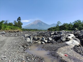 Mount Semeru during the day with a river foreground
