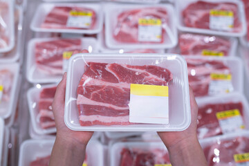 パックに入った豚肉を選ぶ子供の手