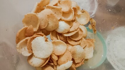 A clear bowl filled with crispy, thin, round crackers.