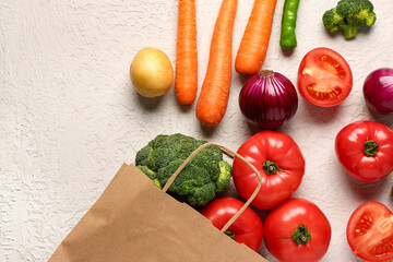Paper bag with different fresh vegetables on white background