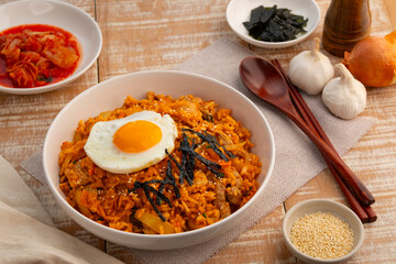Kimchi fried rice with pork topped with fried egg sesame seed and Crispy Seaweed in white plate.Korean food.