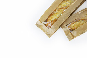 Two freshly baked baguettes, wrapped in brown paper bag, Artisan French baguettes with crispy crusts in paper packaging. Isolated on a white background. Closeup. Copy space

