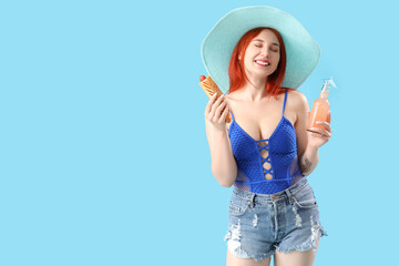 Beautiful young woman with french hot dog and lemonade on blue background