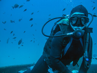 A girl with long blonde hair dive on a wreck off the Mediterranean island of Malta