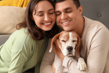 Young couple with cute Beagle dog at home, closeup