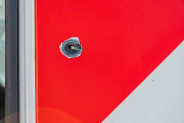 Damage after shelling. Bullet holes in the red metal. Old rusty surface. Textured background. Consequence of attack, war. Dirt and roughness.