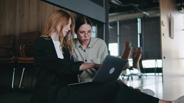 In a modern office setting, two women are skillfully collaborating on a laptop, demonstrating their commitment to teamwork and innovative solutions as they share ideas and insights