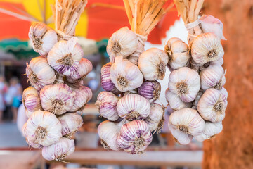 garlic bunches hanging at a vegetables stall at the food market