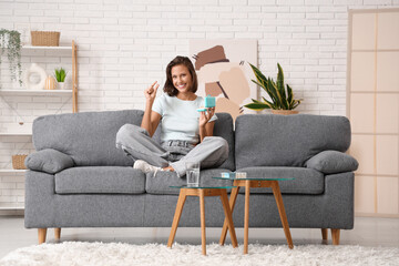 Fototapeta premium Pretty young woman with pill organizer sitting on sofa at home