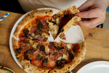 High angle view of Taking a slice of pizza with ham and cheese