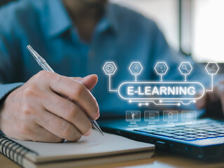A businessman working on a laptop at a desk with various office tools, hand hold pen over a book
