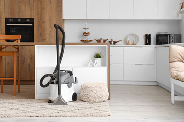 Modern vacuum cleaner on carpet in kitchen