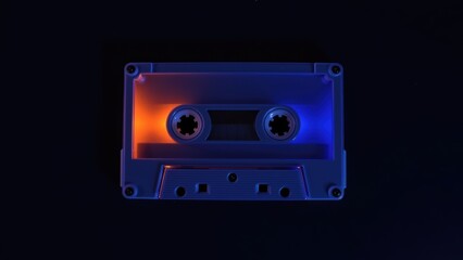 Fototapeta premium Brightly Illuminated Retro Audio Cassette with Vibrant Neon Blue and Orange Colors on a Dim Background