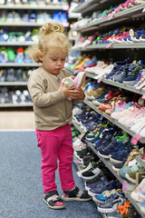 A little girl chooses children's shoes in a shoe store.