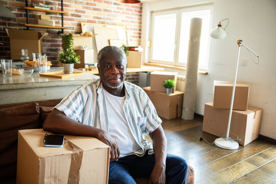 Portrait of a senior man in modern home with moving boxes around
