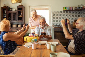 Happy senior man celebrating birthday with friends at home