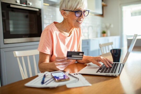 Senior woman shopping online with credit card and laptop at home
