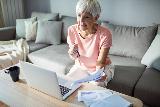 Senior woman managing finances on laptop at home