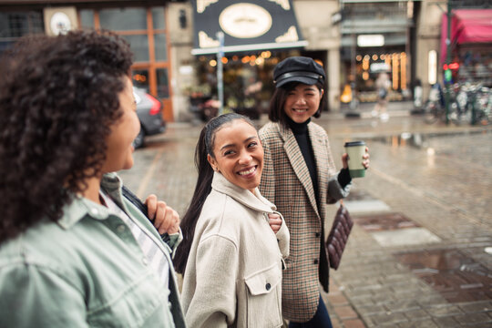 Three diverse female friends walking together on city street