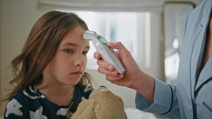 Woman measuring temperature daughter at home closeup. Caring mother small girl
