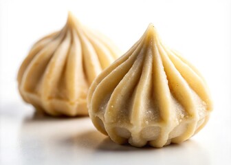A shallow depth of field isolates a single modak from the rest, as the creamy filling and delicate texture take center stage against a clean