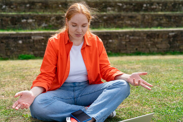 A Young Woman Spreads Hands and Looks at Laptop in Surprise in a Serene Outdoor Setting During a...