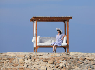 beautiful brunette woman relaxing in gazebo on seashore