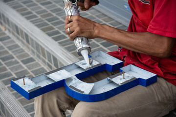 worker installing lettering on commercial metal sign