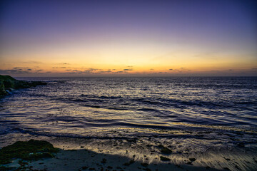2023-12-31 A MOODY SUNSET ALONG THE LA JOLLA COASTLINE WITH CLAM WATERS AND A YELLOW TINT ON TH EHORIZION NEAR SAN DIEGO CALIFORNIA-