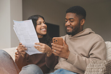 Couple Enjoying a Cozy Moment Together While Reviewing Documents and Using a Smartphone Indoors