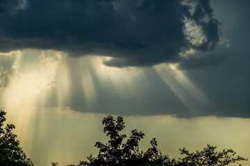 Sun rays breaking through dark rain clouds