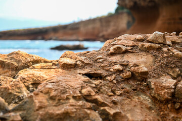 Ocean waves crashing on a rocky shore with a large rock formation in the foreground and blue sky