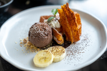 Waffle with chocolate ice cream served with cookie crumble, whipped cream and banana on plate