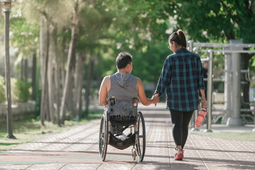 Girlfriend and Disabled man in wheelchair at the park. Muscular dystrophy. Young man in wheelchair...