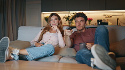 Young pair watching television switching channels couch. Couple choosing movie