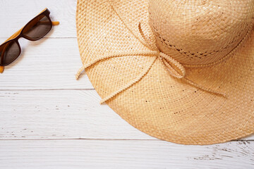 top view of Straw floppy hat and yellow sun glasses on white wooden background , represent holiday and beach in summer concept