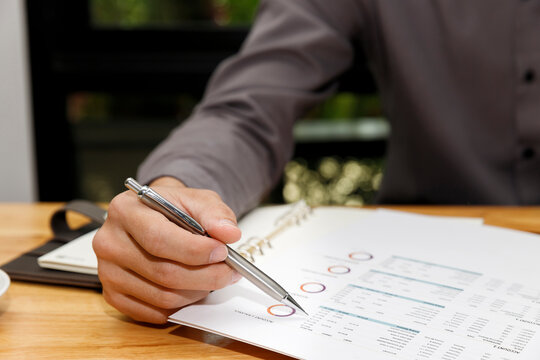 Businessman holding a pen with documents in home office.