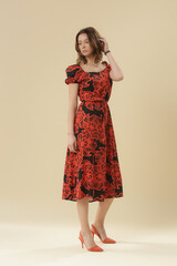 Serie of studio photos of young female model in black and orange midi dress with short puff sleeves
